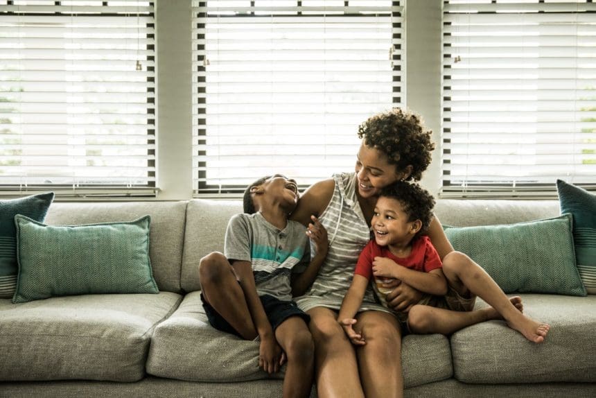 Single mother and her two sons sitting on a couch laughing together