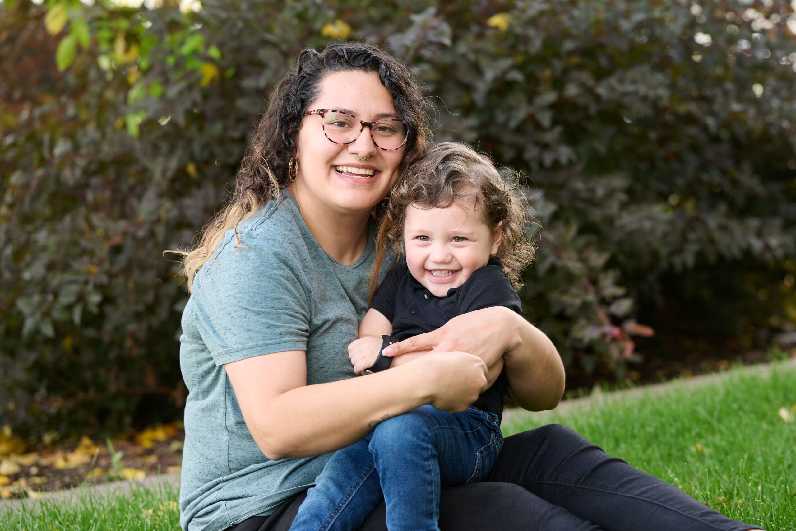 Mother and child seated, smiling, outdoors